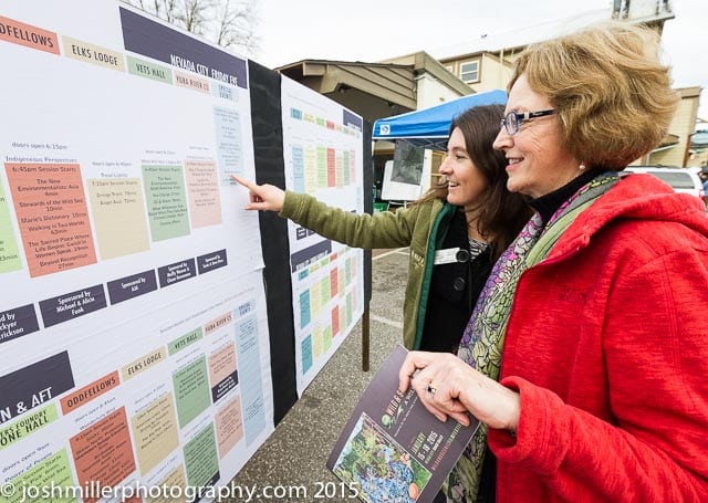 Two women checking out the bulletin board with the festival schedule