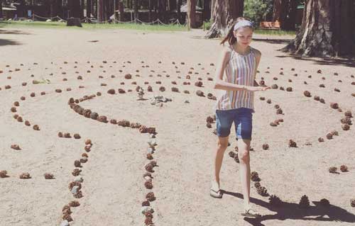 Earth art: a child walks through a pinecone labyrinth